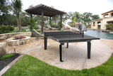 Outdoor ping pong table in a backyard setting with a pool and patio.