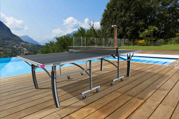 Outdoor ping pong table on a wooden deck with a pool and scenic background