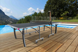 Outdoor ping pong table on a wooden deck with a pool and scenic background